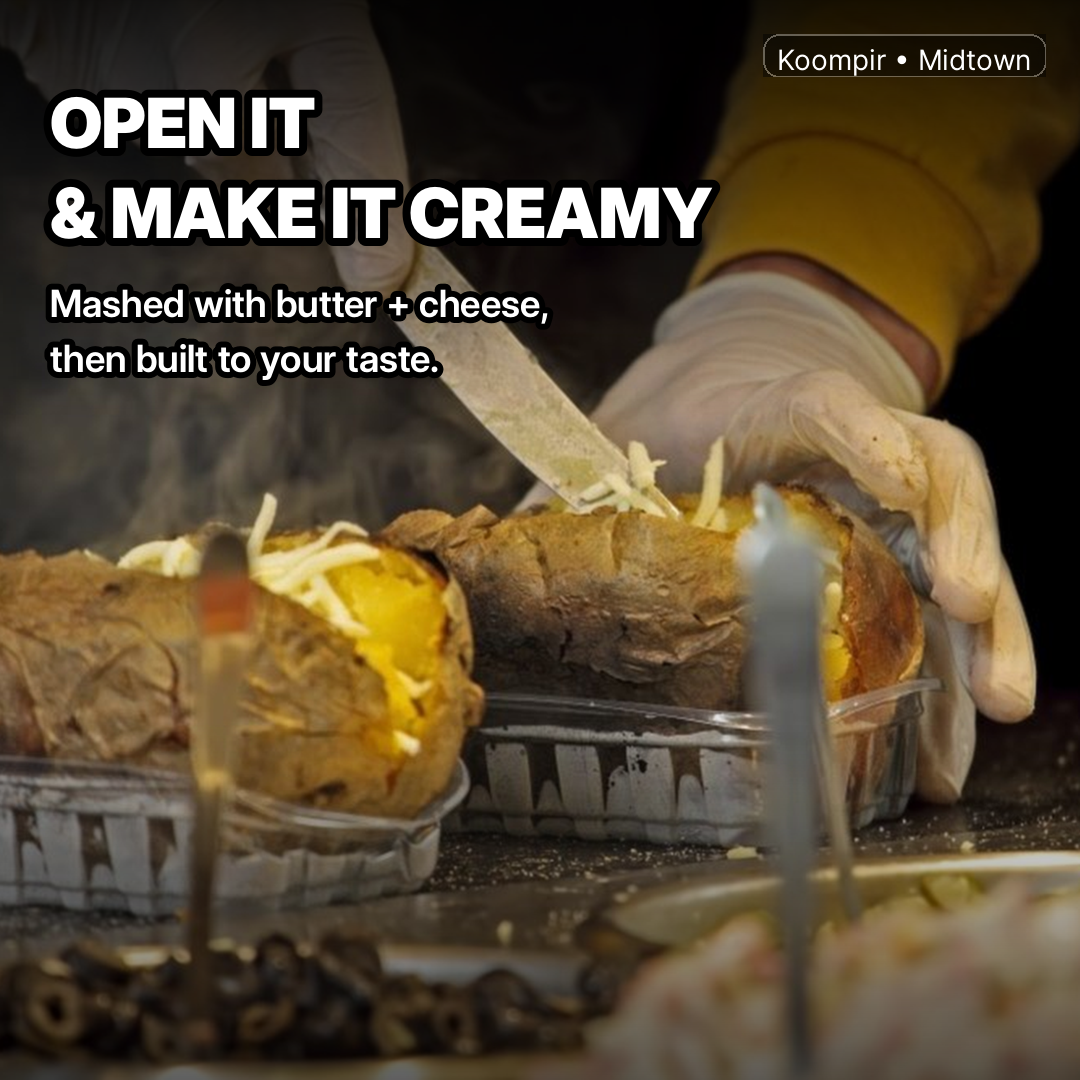 Butter and cheese being mashed into kumpir baked potato with a knife
